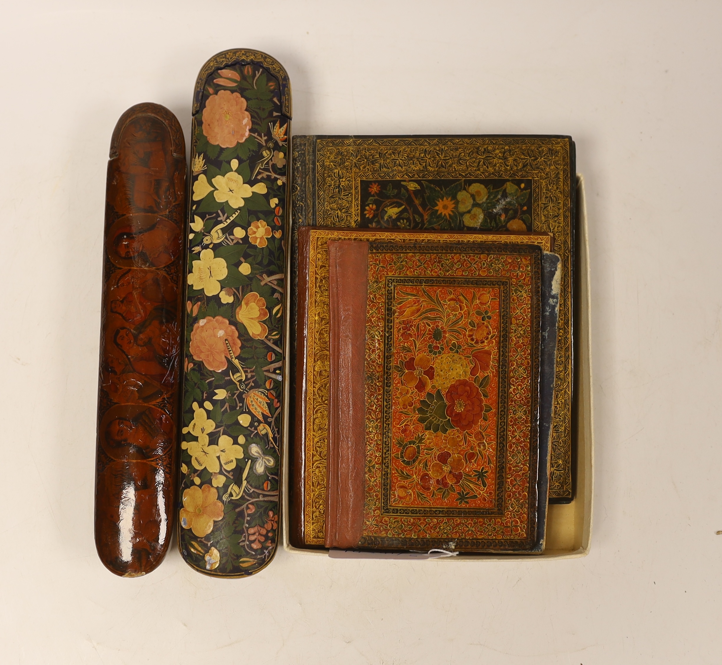 A Persian scribe’s pen box, painted with ladies and animals, another similar with printed floral decoration and other Persian and Kashmiri lacquer blotter /book covers largest cover 13.5 cm wide x 18cm high